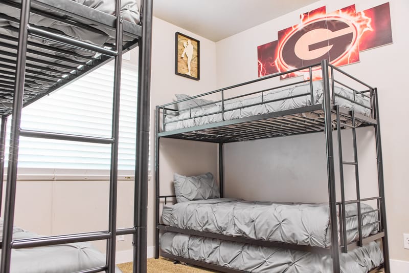 The Cowboy Bunk Room, with two steel-frame bunk beds and a pennant on the wall.