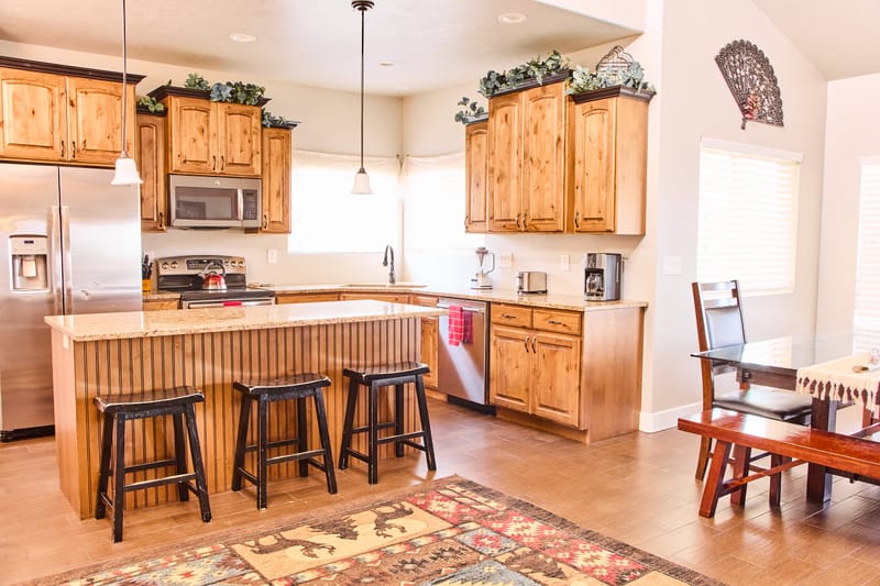 The kitchen, with knotty alder cabinets, a full-size range, and an island with four stools along one side.